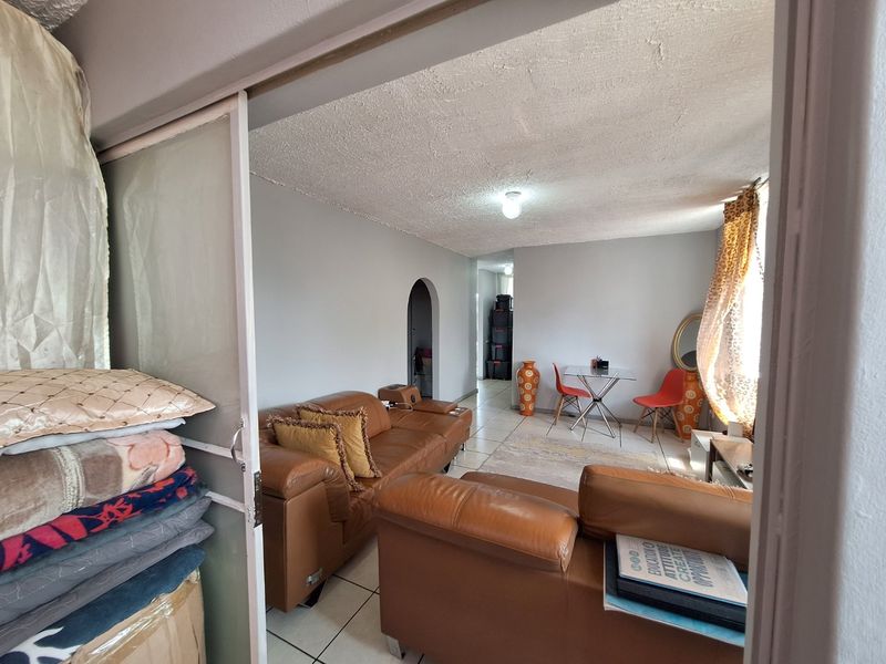 A living room area featuring tiled flooring, an arched doorway, and a sliding door entrance, offering a functional layout for comfortable living.