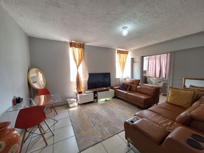 A living room featuring tiled flooring and a textured ceiling, with a sliding door leading to an adjacent space.
