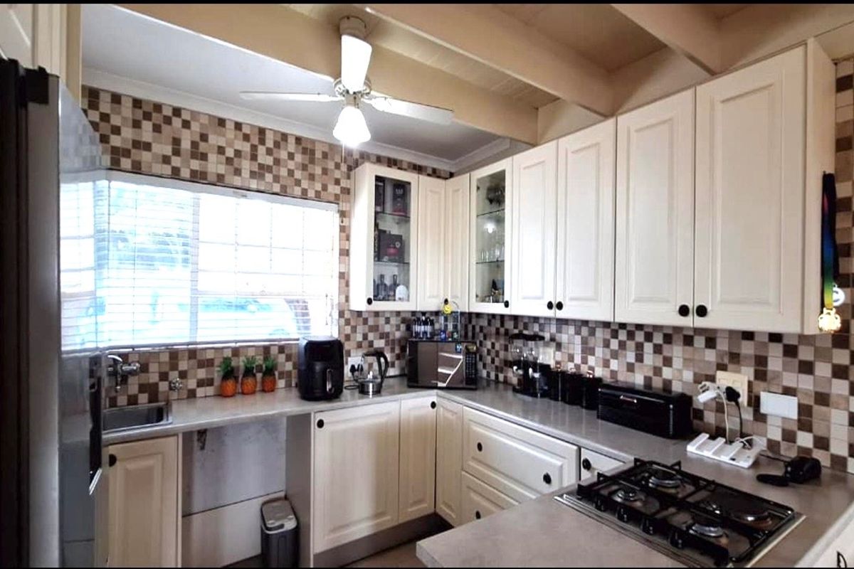 A functional kitchen featuring white cabinetry, a gas cooktop, tiled backsplash, and a ceiling fan, offering a practical layout for daily meal preparation.