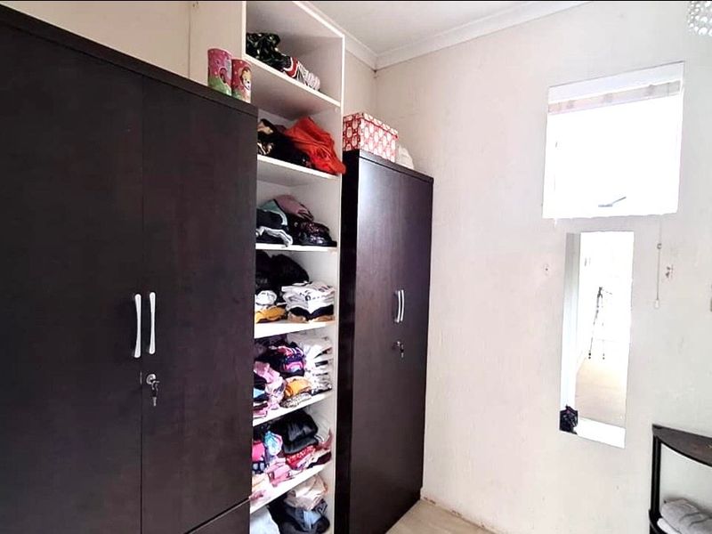 A bedroom featuring dark wood built-in cupboards with integrated shelving and coving detail.