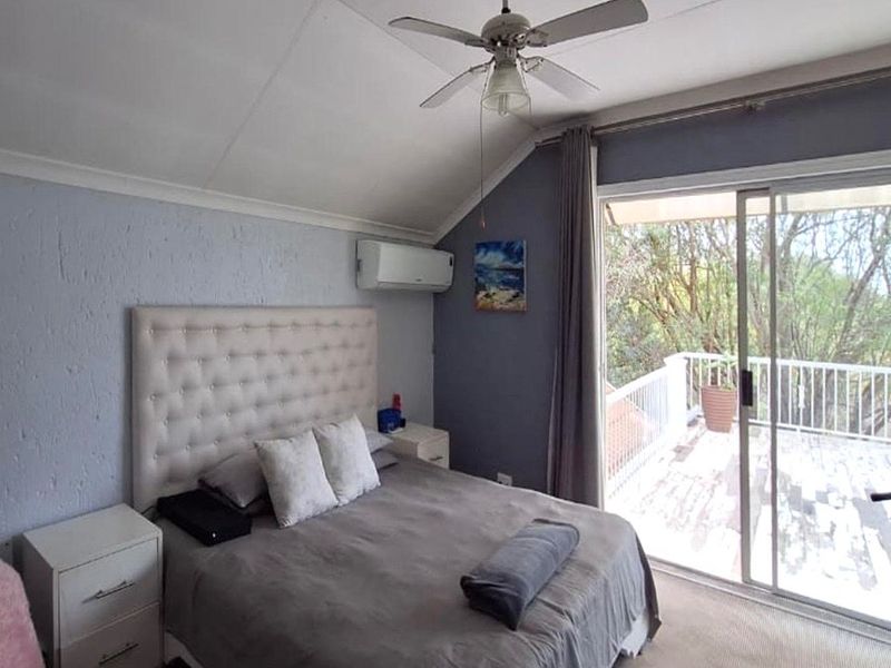 A bedroom featuring a vaulted ceiling, ceiling fan, split-system air conditioning, and sliding glass doors providing direct access to an outdoor balcony.