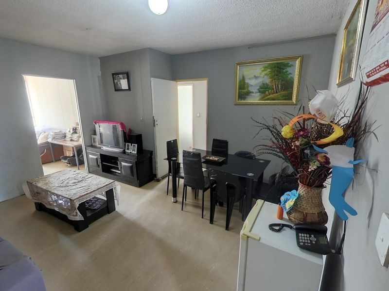 An open-plan living and dining area featuring neutral wall tones, textured ceilings, and direct access to adjacent rooms.
