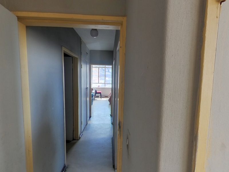 A functional interior hallway connecting multiple rooms, featuring neutral wall tones and standard door frames, requiring minor cosmetic updates.