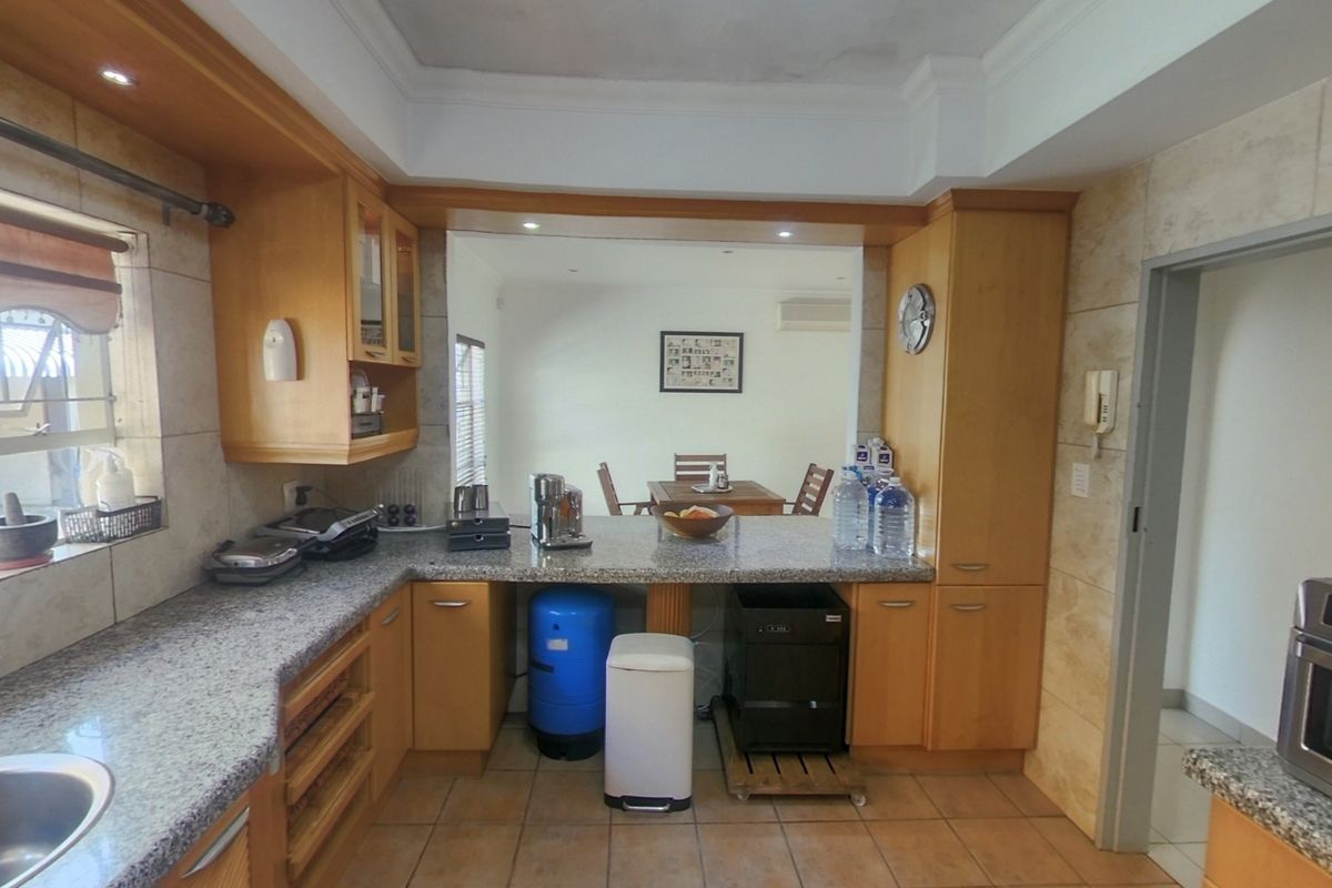 A functional kitchen featuring granite countertops, wooden cabinetry, and a built-in oven, with a pass-through window connecting to the adjacent dining area.