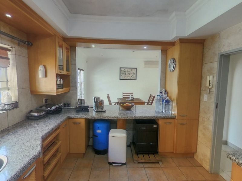 A functional kitchen featuring granite countertops, wooden cabinetry, and a built-in oven, with a pass-through window connecting to the adjacent dining area.