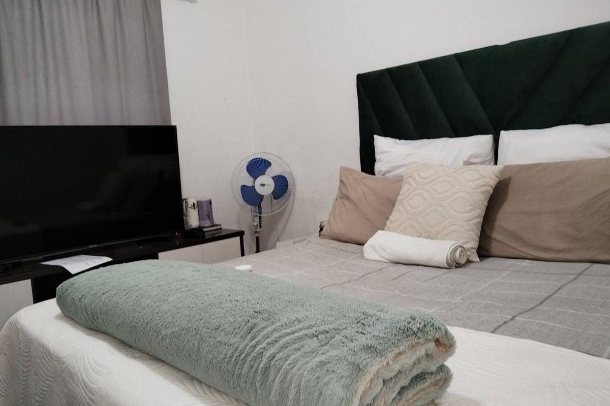 A bedroom featuring a dark green upholstered headboard and neutral wall finishes.
