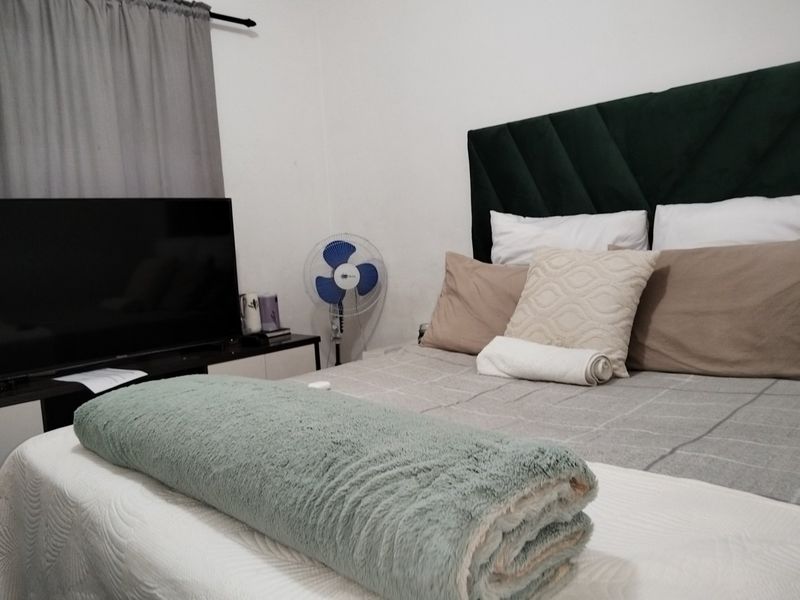 A bedroom featuring a dark green upholstered headboard and neutral wall finishes.