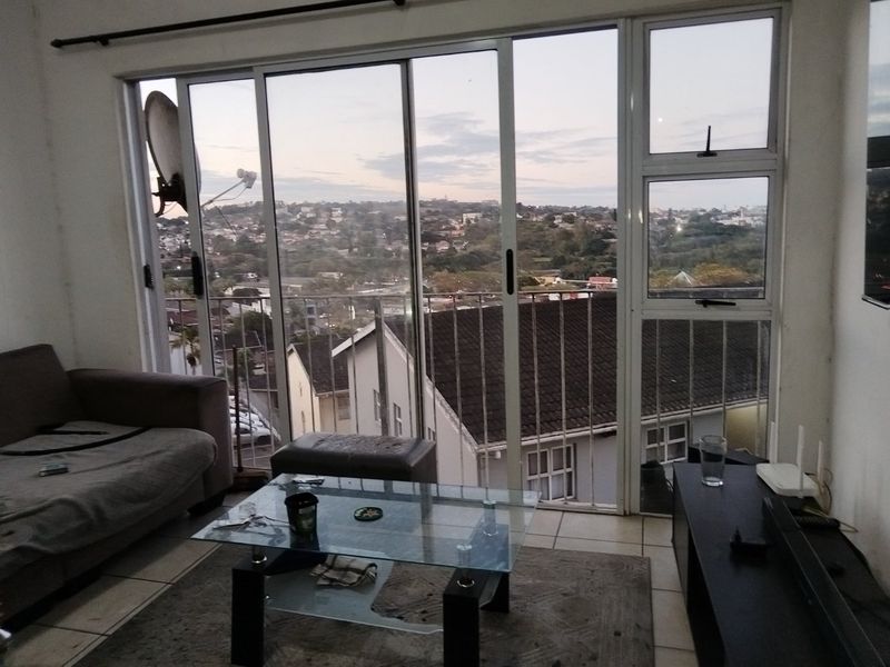 Living room featuring large sliding glass doors that open to a balcony with expansive suburban views and tiled flooring throughout.
