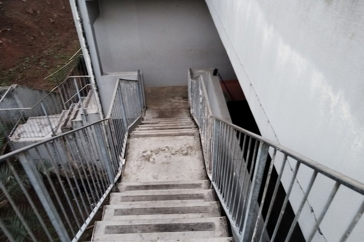 An outdoor concrete staircase with metal railings providing access to the rear of the property.