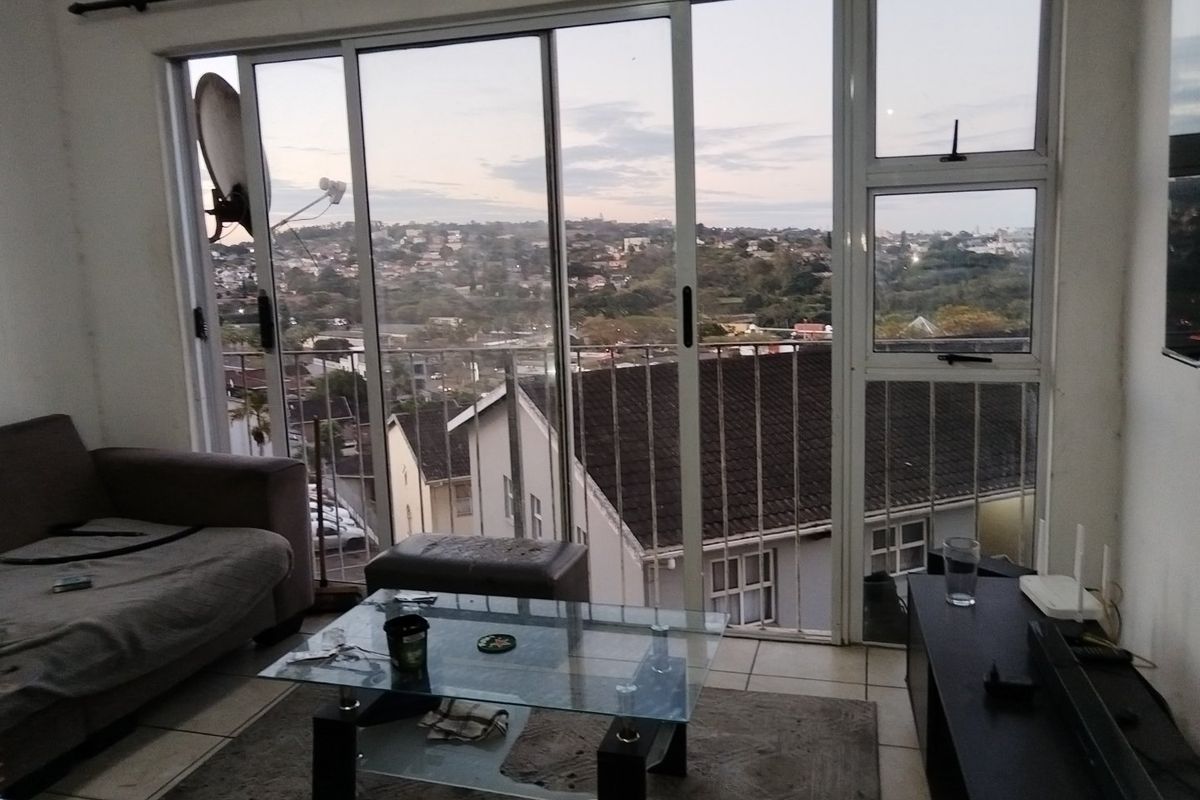 Living room featuring large sliding glass doors that open to a balcony with expansive suburban views and tiled flooring throughout.