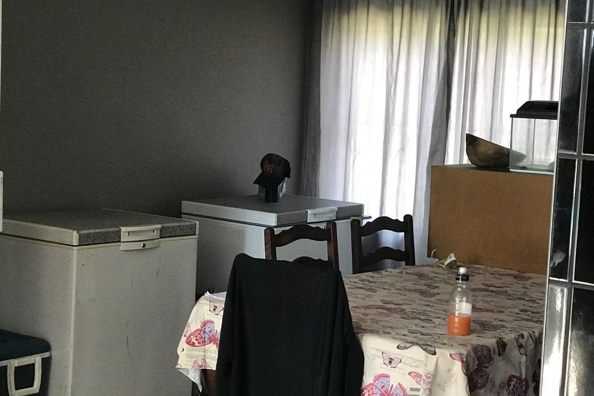 A living area featuring dark painted walls and window curtains, currently utilized for storage with chest freezers present.