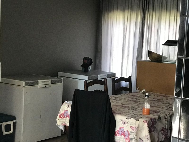 A living area featuring dark painted walls and window curtains, currently utilized for storage with chest freezers present.