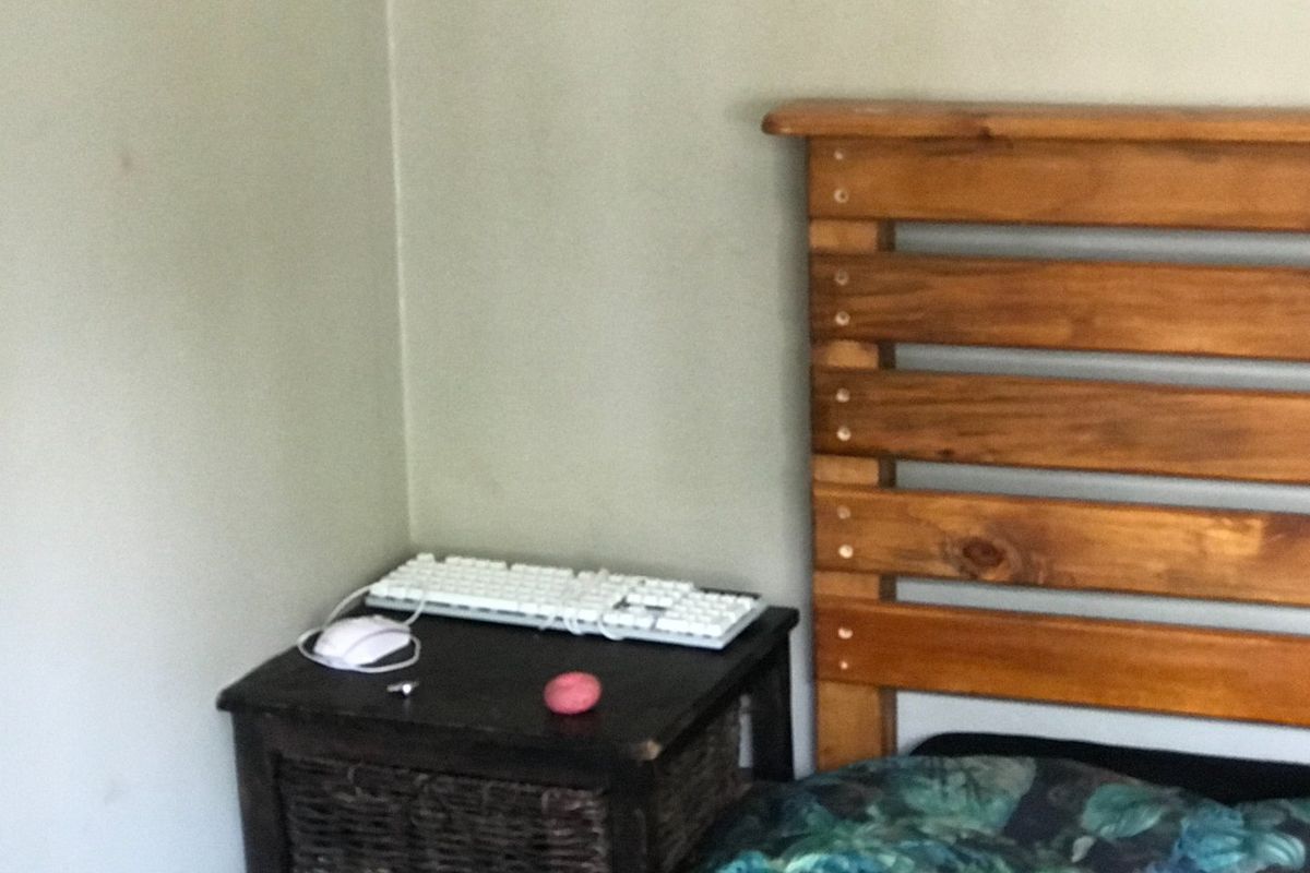 A close-up view of a bedroom corner featuring a wooden headboard and wall space.