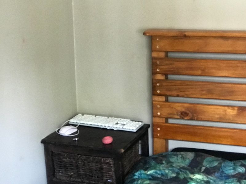 A close-up view of a bedroom corner featuring a wooden headboard and wall space.