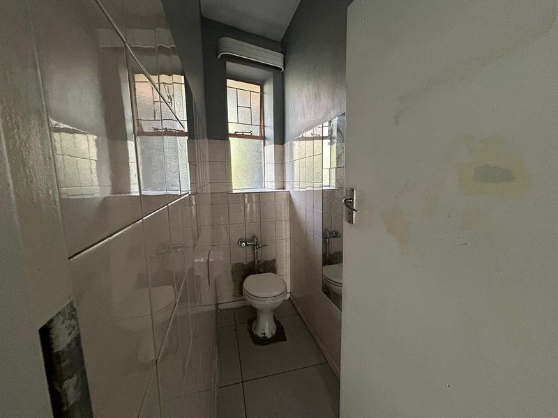 A small, dated bathroom featuring tiled walls and floor, requiring renovation and cosmetic repairs to improve its overall condition and functionality.