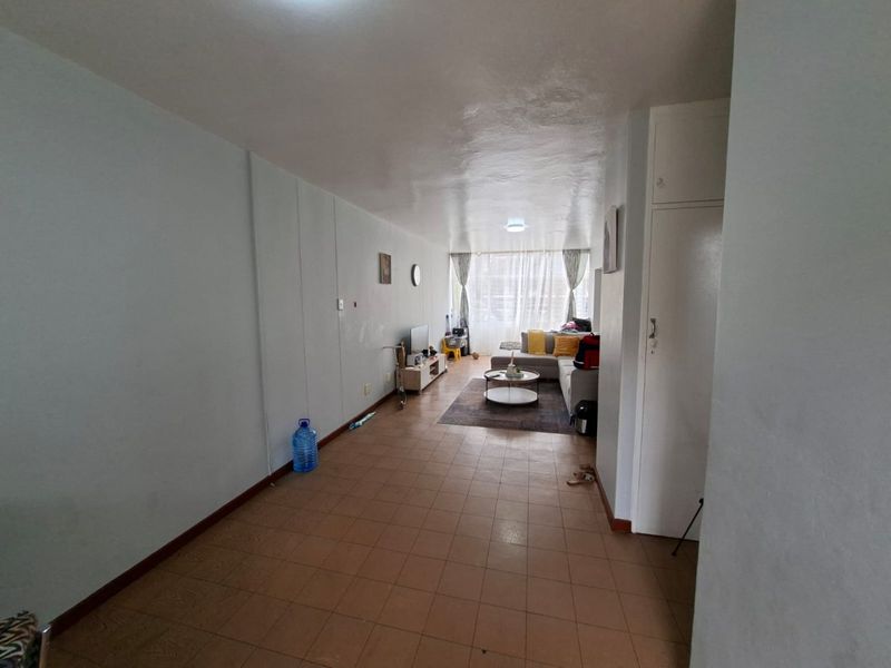 A spacious living area featuring tiled flooring and a built-in storage cupboard, offering a functional layout with natural light from the window.