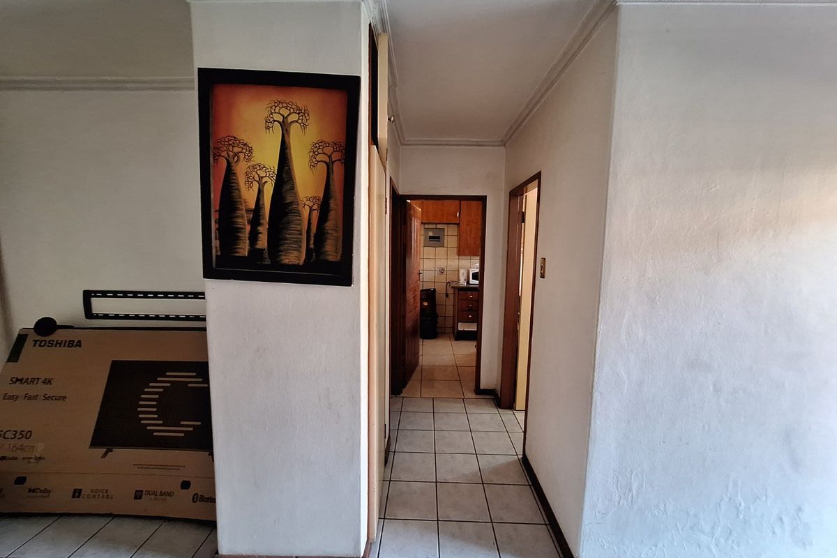A tiled hallway providing access to adjacent rooms, featuring neutral walls and traditional cornicing.