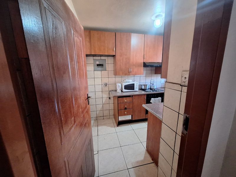 A functional kitchen featuring laminate cabinetry, tiled backsplash, and built-in cooking appliances, offering a practical layout for daily meal preparation.