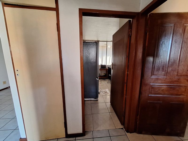 A functional hallway area featuring tiled flooring and wooden door frames, providing access to adjacent rooms within the apartment.