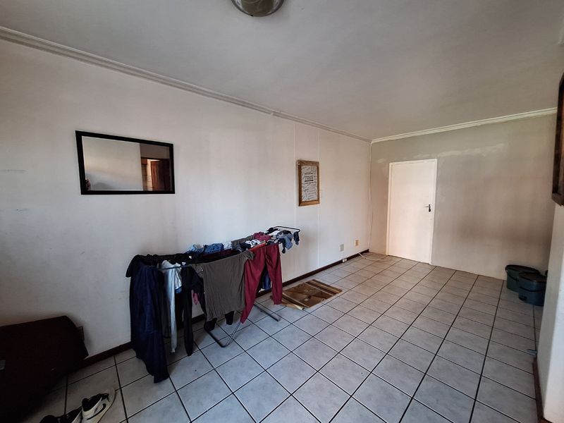 An empty living area featuring tiled flooring and neutral walls, offering a blank canvas for interior design and personalization.