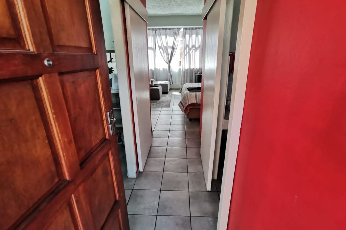 A view through a hallway with tiled flooring and sliding doors leading into a bedroom area.