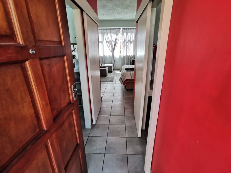 A view through a hallway with tiled flooring and sliding doors leading into a bedroom area.
