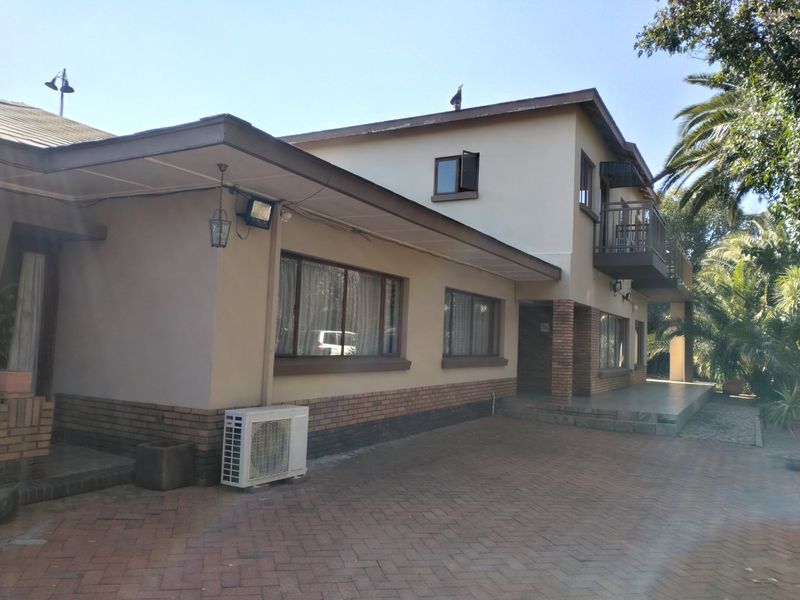 Rear exterior view of a two-story house featuring brick paving, a balcony, and an integrated air conditioning unit.