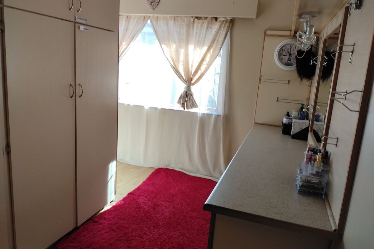 Bedroom featuring built-in cupboards and a built-in vanity unit with laminate flooring and natural light.