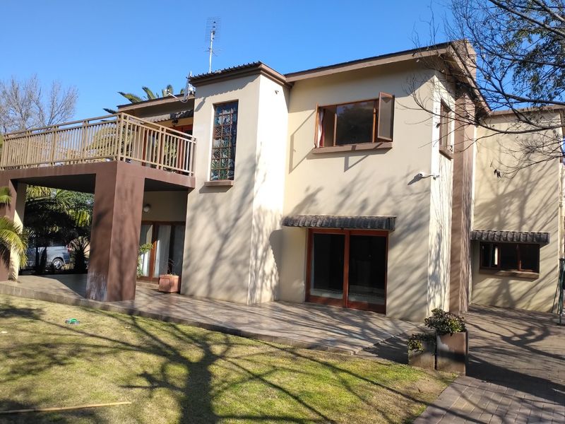 Rear view of a two-story house featuring a tiled patio, a spacious upper-level balcony with metal railings, and sliding glass door access.