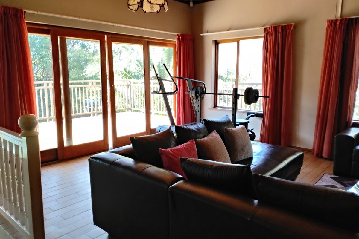 Spacious living room featuring timber-framed sliding doors opening to a balcony, tiled flooring, and a warm timber ceiling.