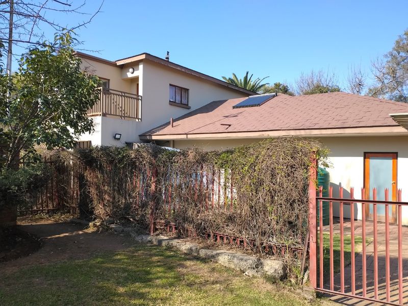Rear view of the property featuring a balcony, solar water heater, and a fenced garden area with paved access.