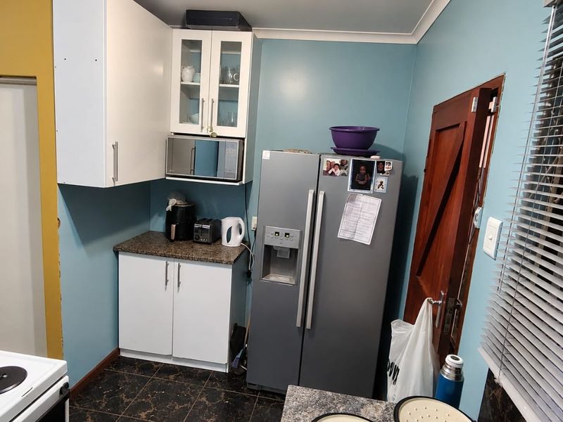 A functional kitchen featuring white cabinetry, laminate countertops, and dark tiled flooring, providing a practical workspace with integrated microwave and ample storage.
