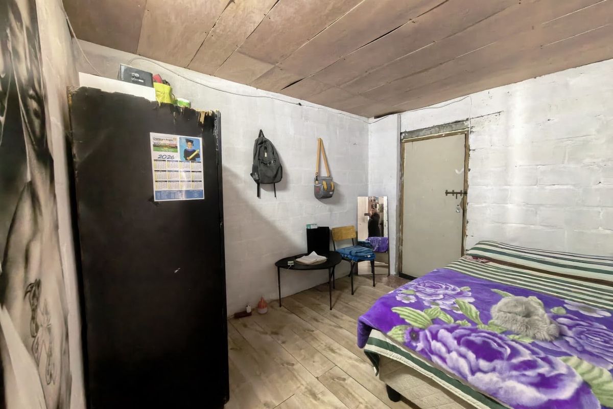 A basic bedroom featuring painted blockwork walls, a timber plank ceiling, and tiled flooring, requiring cosmetic updates to improve the overall finish.