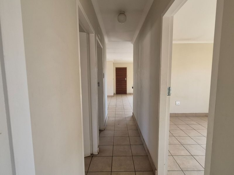 A functional hallway featuring neutral tiled flooring and access to multiple rooms, providing a clean and simple transition space within the home.