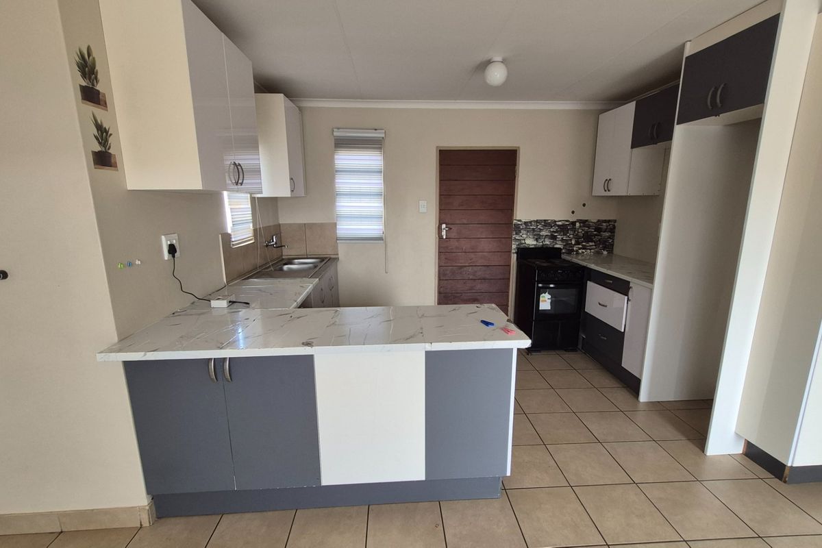 A functional kitchen featuring two-tone cabinetry, marble-look countertops, tiled flooring, and a freestanding stove, offering a clean and practical workspace.