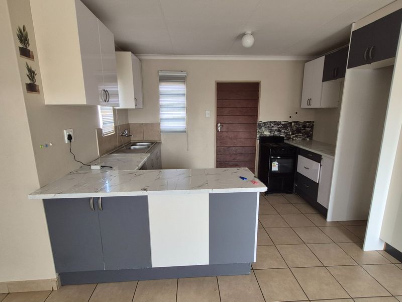 A functional kitchen featuring two-tone cabinetry, marble-look countertops, tiled flooring, and a freestanding stove, offering a clean and practical workspace.