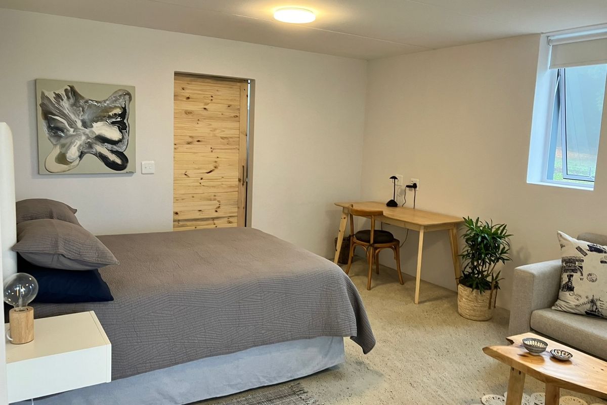 A well-lit bedroom featuring neutral walls, a sliding wooden door, and a casement window, providing a comfortable and functional living space.
