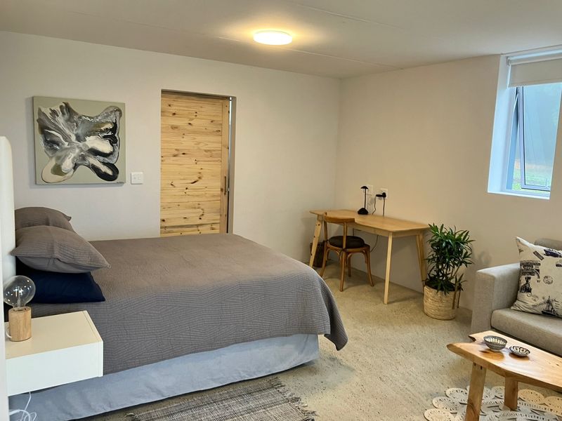 A well-lit bedroom featuring neutral walls, a sliding wooden door, and a casement window, providing a comfortable and functional living space.