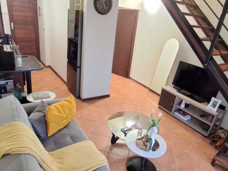 Open plan living area featuring tiled flooring and a staircase with a metal handrail, providing access to the upper level of the apartment.