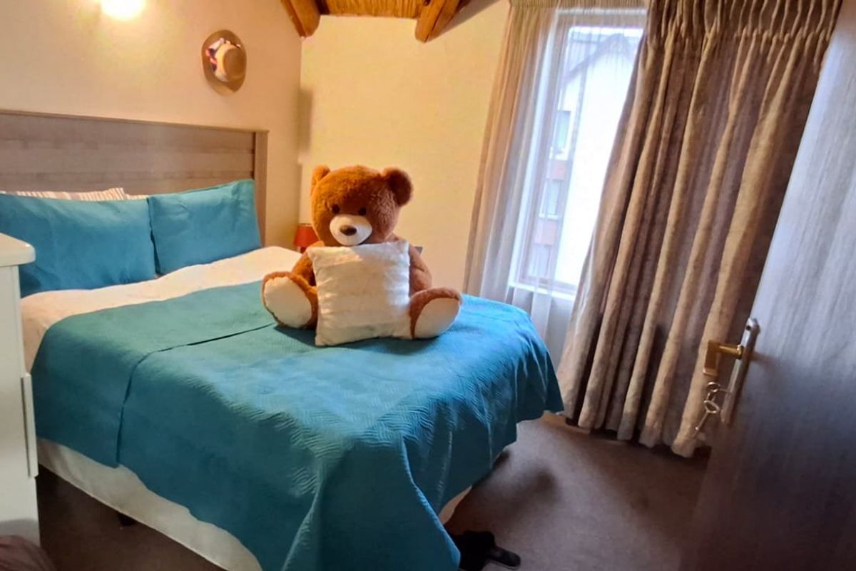A cozy bedroom featuring exposed timber ceiling beams and large windows with fitted curtains, providing a warm and inviting atmosphere.
