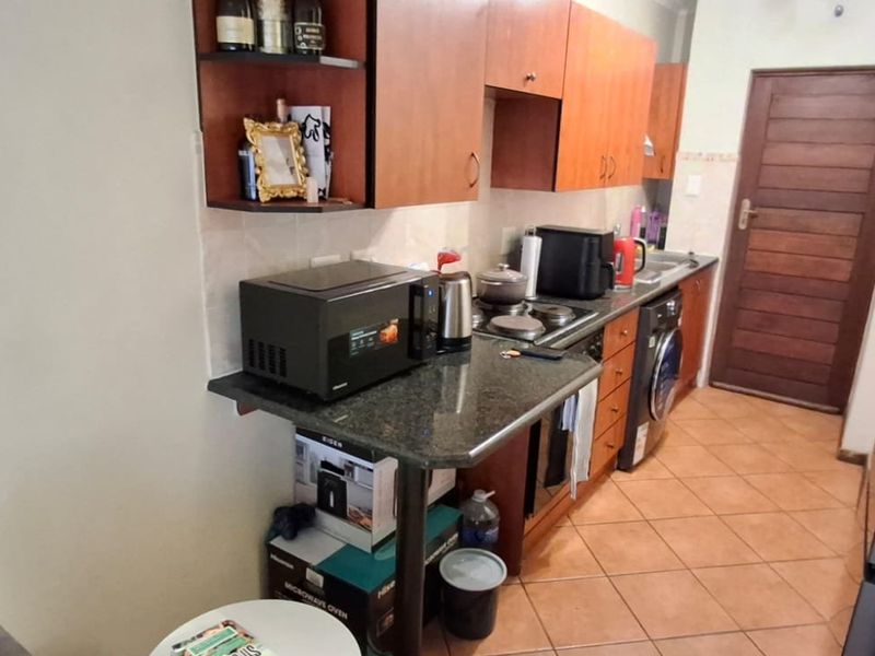 A functional kitchen featuring wooden cabinetry, granite countertops, a built-in hob and oven, and tiled flooring, providing a practical workspace.