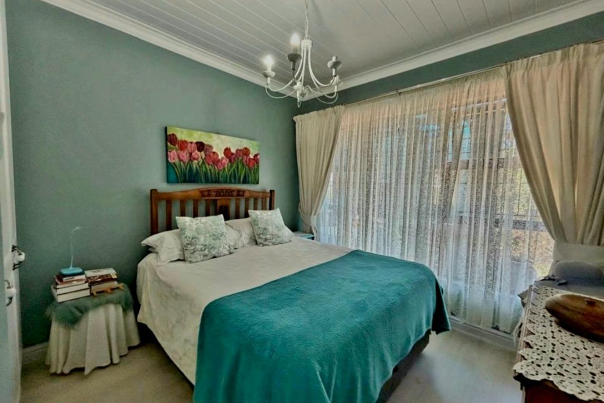 A well-maintained bedroom featuring a tongue and groove ceiling, decorative chandelier, and large window allowing for natural light.