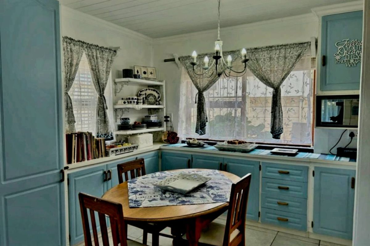 A cozy kitchen featuring blue built-in cabinetry, tiled flooring, and a classic chandelier, offering a functional space with a traditional aesthetic.