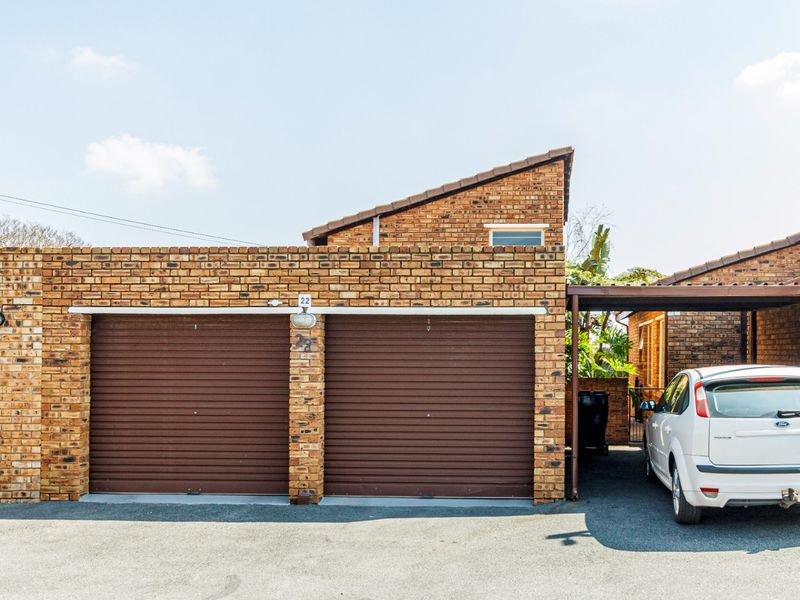 A double garage with face brick exterior and an adjacent carport, providing secure parking and additional covered space.