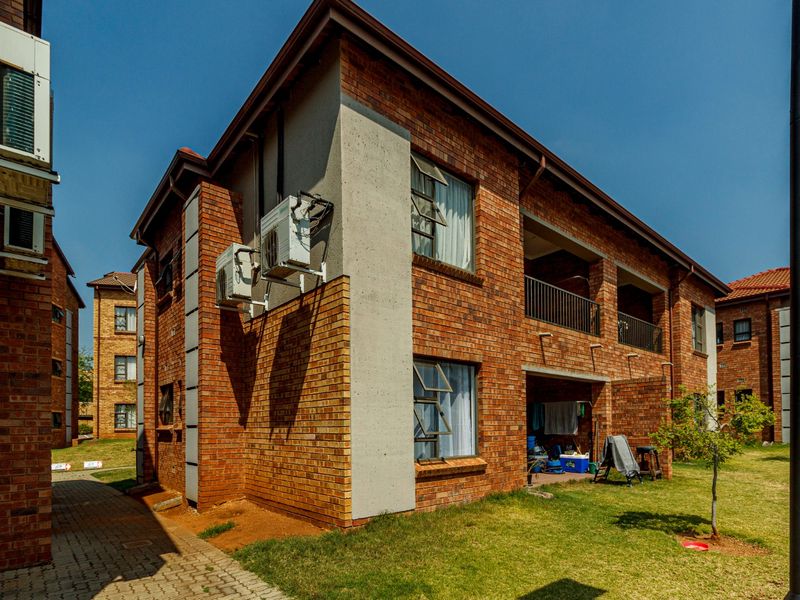 Exterior view of a multi-story face brick apartment building featuring concrete accents, external air conditioning units, and a paved walkway.