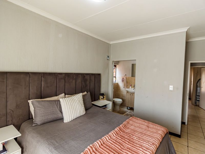 A bedroom featuring tiled flooring and an adjoining en-suite bathroom, providing a functional layout with neutral wall finishes.
