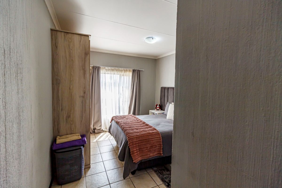 A functional bedroom featuring tiled flooring and neutral wall finishes, offering a comfortable and practical living space.