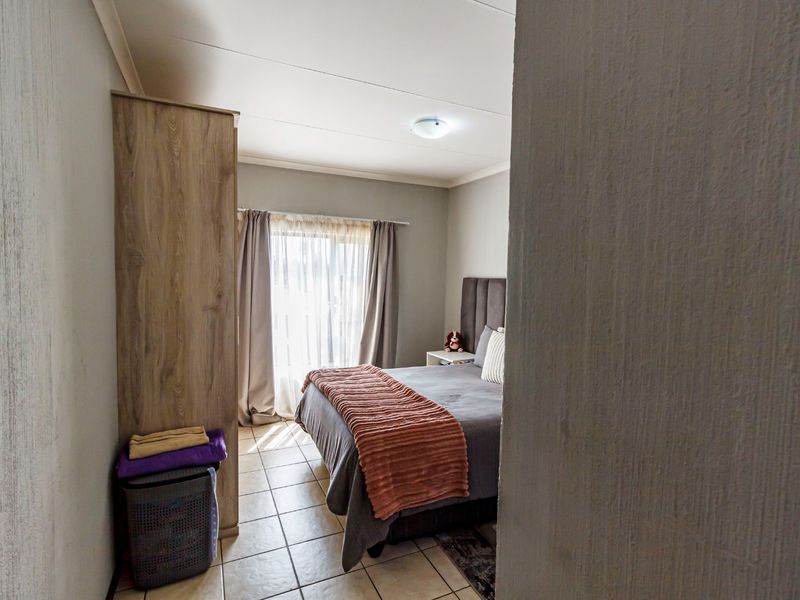 A functional bedroom featuring tiled flooring and neutral wall finishes, offering a comfortable and practical living space.