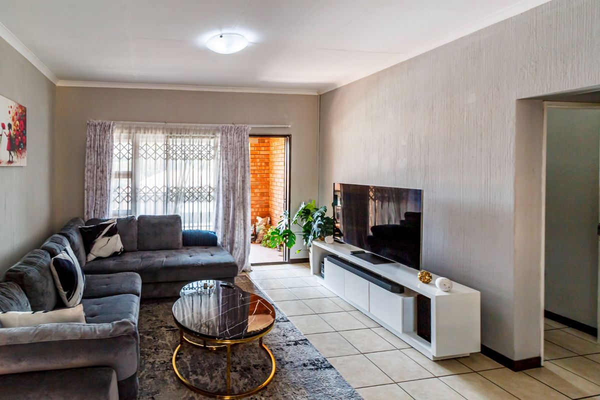 A comfortable living room featuring tiled flooring, neutral walls, and direct access to an outdoor patio area through a sliding door.