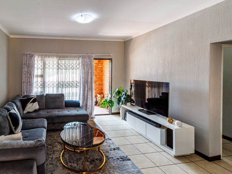 A comfortable living room featuring tiled flooring, neutral walls, and direct access to an outdoor patio area through a sliding door.